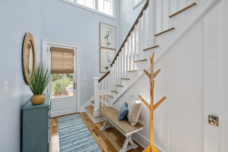 Townhome entry: light-oak console table, small mirror, woven basket, neutral runner, sabal palm beyond.