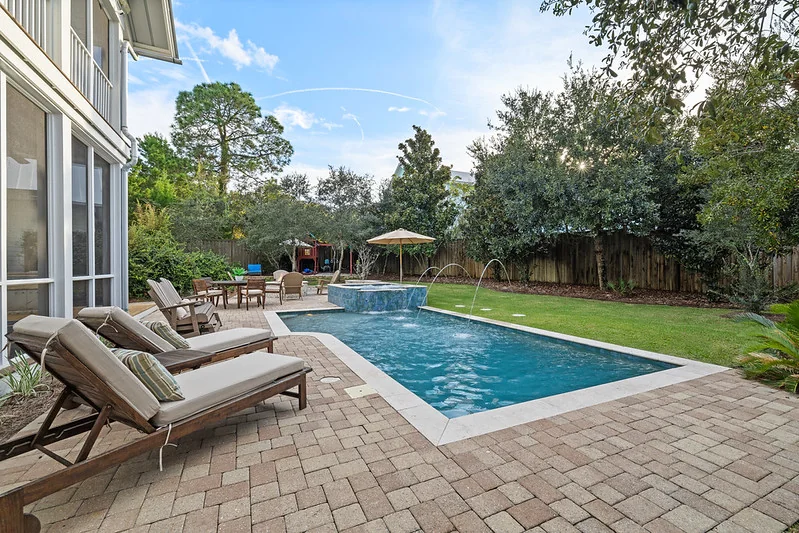 Composed Florida pool deck: 4 UV-rated loungers under louvered pergola, six-seat dining, lounge cluster, screened cage.