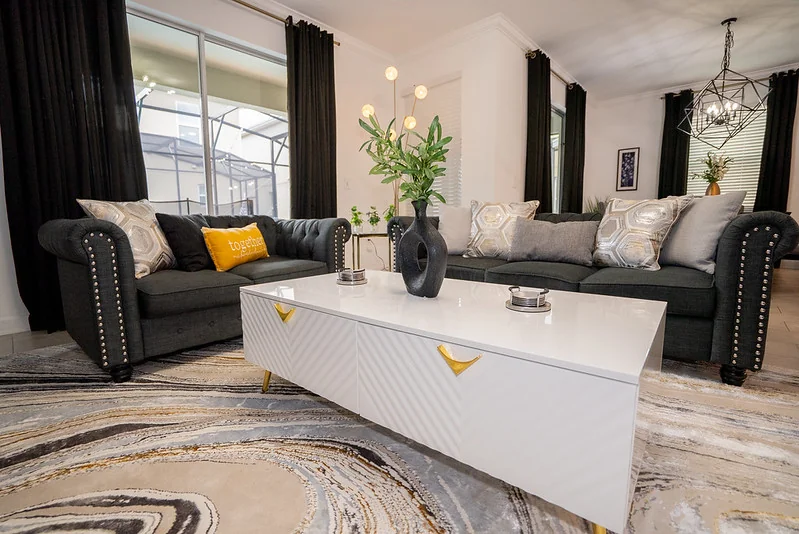 9BR Reunion luxury estate great room: facing performance-velvet sectionals, sculptural chandelier, 98" wall TV in custom millwork.