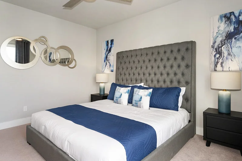 Luxury primary: king with sculptural teal-velvet headboard, custom bedside millwork, sitting lounge with designer swivels.